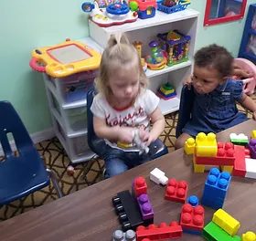 Two toddlers building with blocks